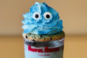 Blue whipped cream with candy googly eyes sits atop a cookie on a milkshake in a glass that says "Awful Awful - It's a drink."