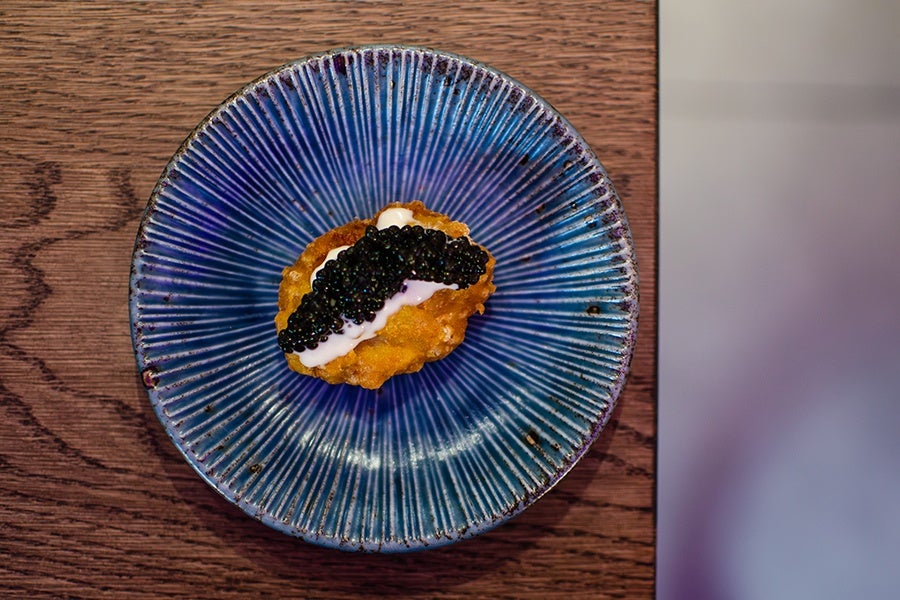A chicken nugget topped with white sauce and caviar.
