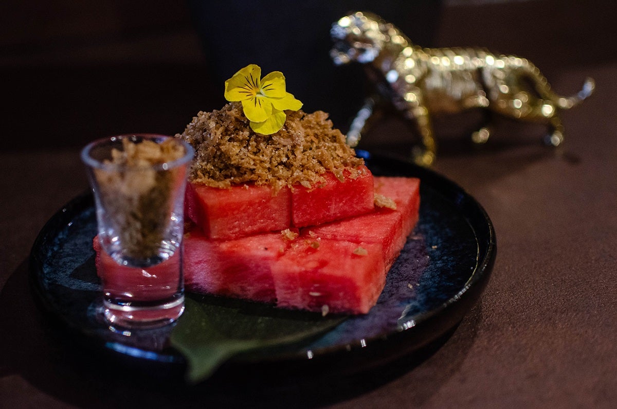 A spread of Thai dishes cover a light wooden table.