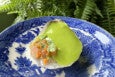 An oyster with green foam and other toppings.