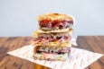 A stack of three meat-and-cheese-filled sandwiches on Tuscan flatbread, which looks like a thinner focaccia.