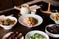 A tablescape of Chinese food, include a noodle dish with shrimp and a teapot.