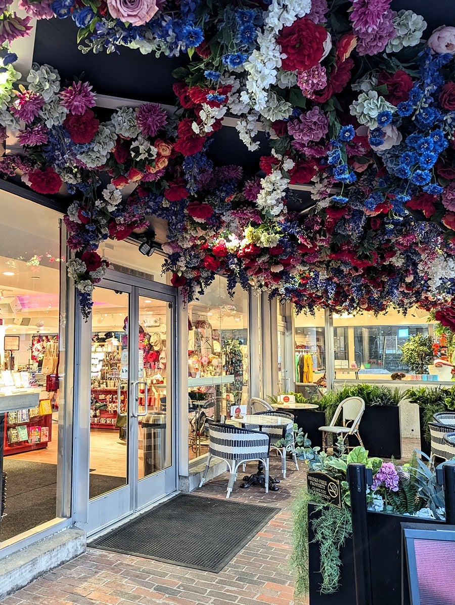 A small patio outside a bookstore is decorated with a floral-covered ceiling.