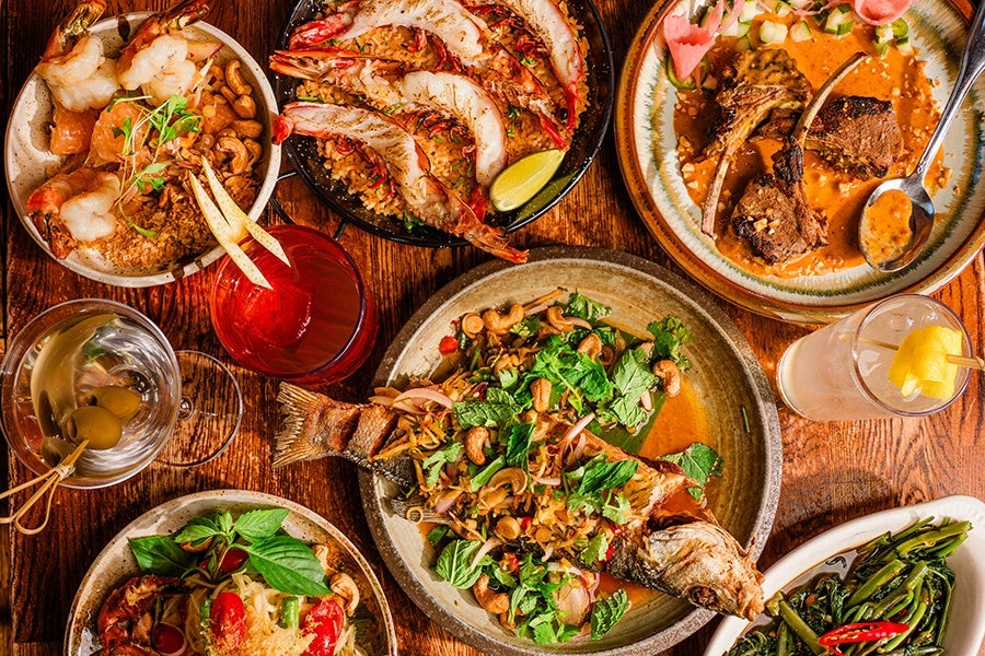 Overhead view of Thai dishes, including an herb-covered whole fish.