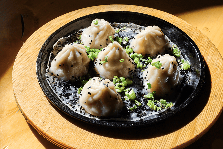 Plump dumplings garnished with chives and black sesame.
