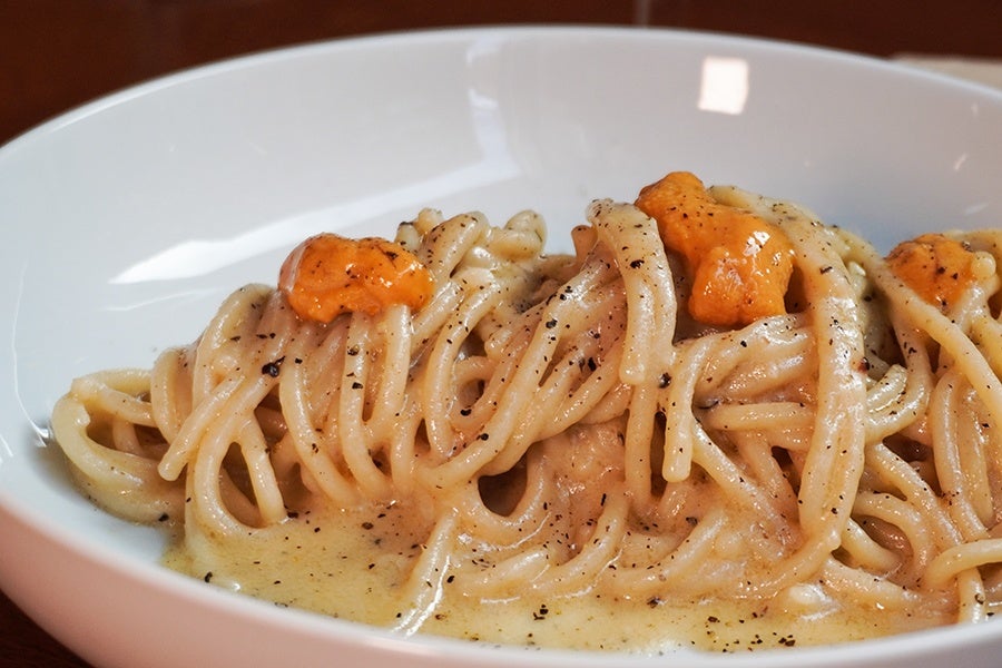 A pile of tonnarelli, the squared-off version of spaghetti, is garnished with black pepper and uni.