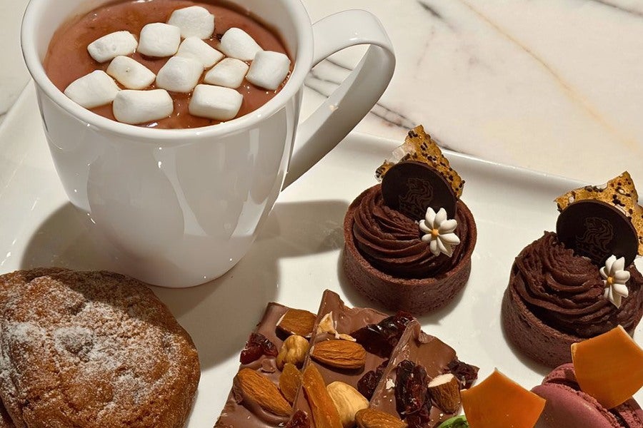 Hot chocolate with marshmallows is accompanied by various chocolate treats.