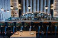 A restaurant bar. The wall behind it is white painted brick, and decorative metal beams rise from the backbar up the wall. A vintage TV is the centerpiece.