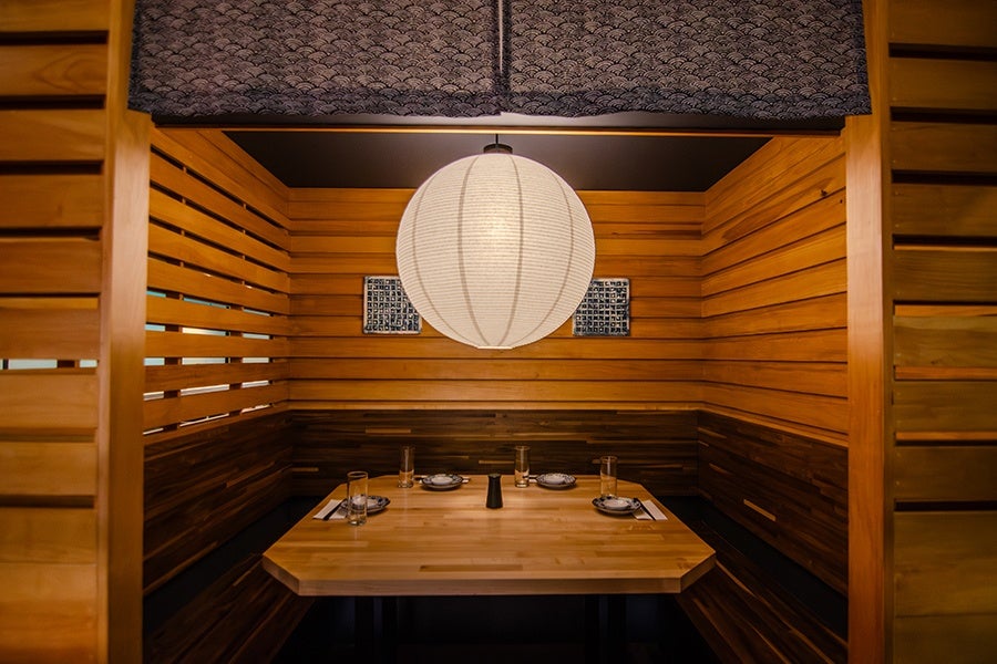A wood-paneled booth with a white paper lantern inside a Japanese restaurant.