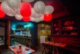 A Japanese restaurant is decorated with red and white paper lanterns and blue neon signage reads "Cafe Sushi."