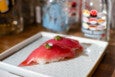 Two pieces of tuna nigiri with a drop of an herb garnish sit on a white plate.