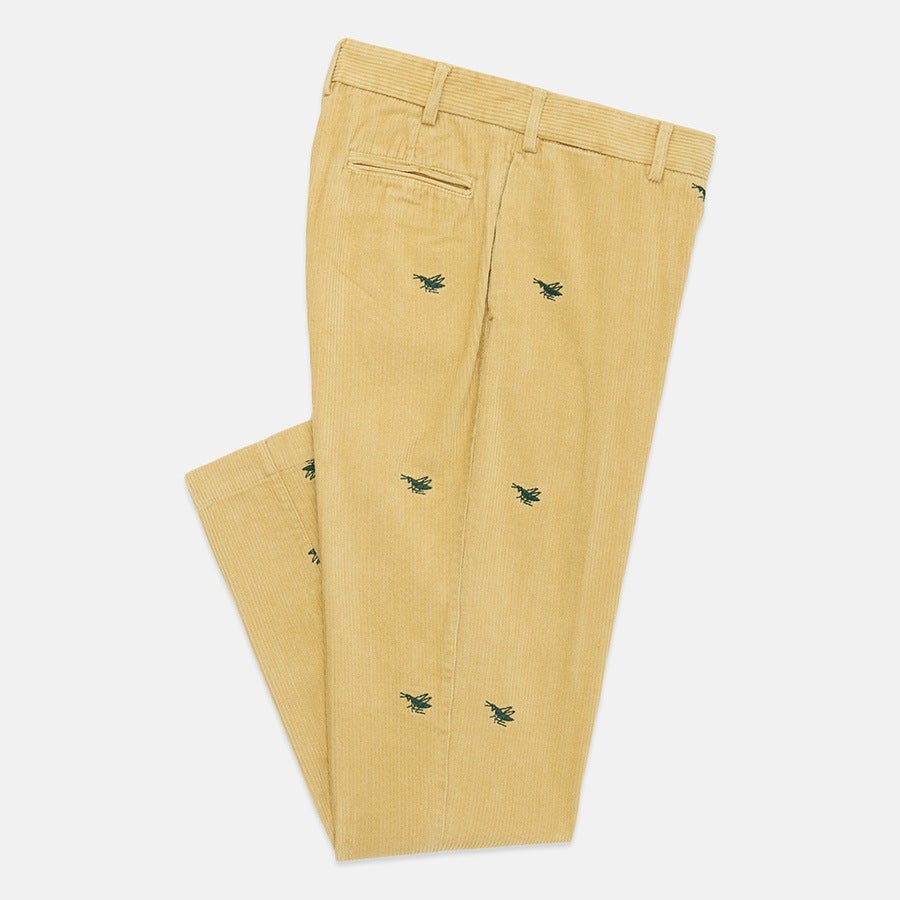 Light yellow corduroy pants with small green embroidered airplane motifs scattered across the fabric, featuring belt loops and a single back welt pocket.