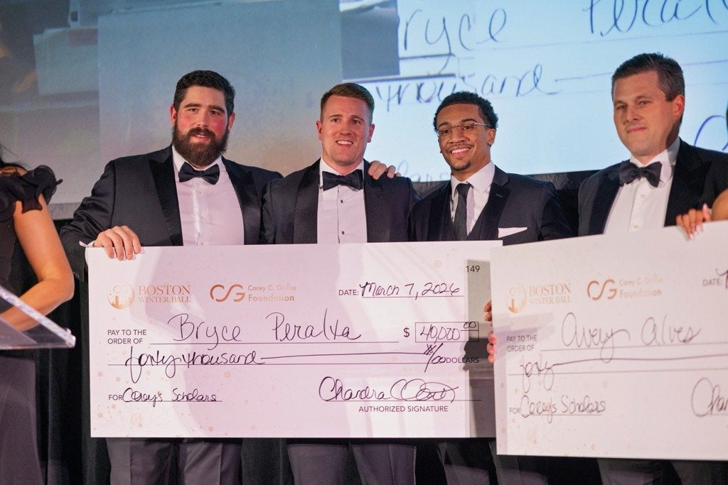 Four men in tuxedos are standing together holding large ceremonial checks. The check on the left is made out to Bryce Peralta for $40,200 from the Corey C. Griffin Foundation and Boston Winter Ball, dated March 7, 2026. The check on the right is partially visible and made out to Avery Alves. The men are smiling and posing for a photo.
