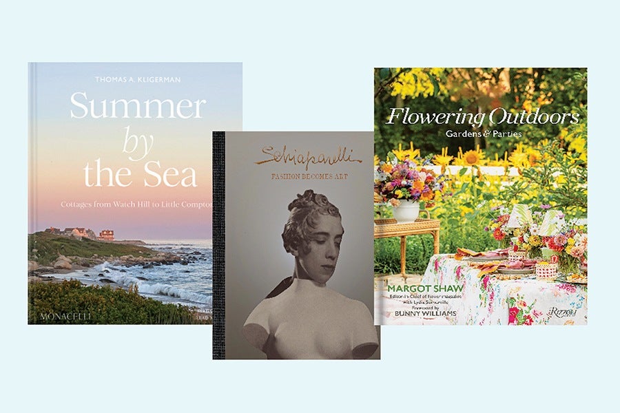 Three books are displayed: "Summer by the Sea" featuring a coastal scene at sunset, "Schiaparelli: Passion Becomes Art" with a black-and-white bust sculpture on the cover, and "Flowering Outdoors: Gardens & Parties" showing a vibrant outdoor table setting with flowers and sunflowers in the background.