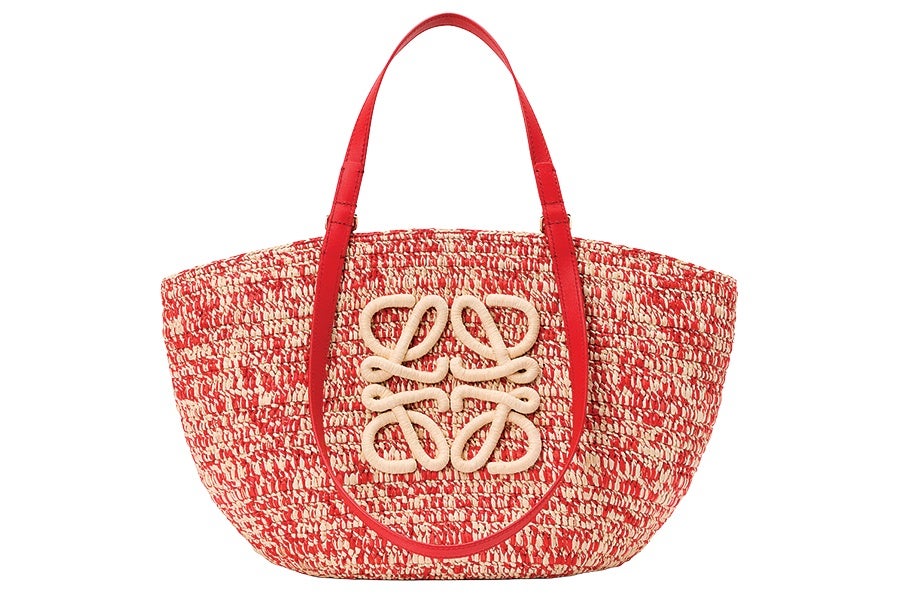 Red and beige woven tote bag with a rounded trapezoid shape, featuring two red leather handles and a beige decorative knot design on the front center.
