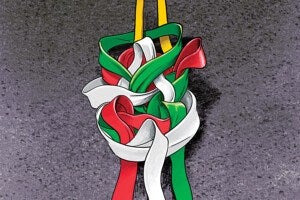 A colorful abstract sculpture composed of intertwined, ribbon-like shapes in red, green, and white, suspended by two yellow straps against a textured gray background.
