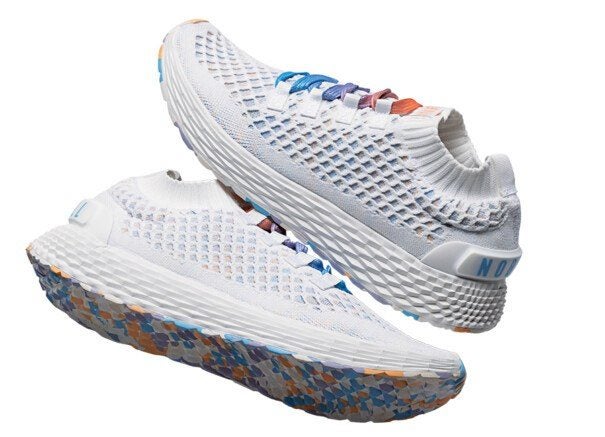 Pair of white athletic shoes with a textured, breathable mesh upper and sock-like ankle collar. The shoes feature multicolored laces in shades of blue, purple, and orange. The soles are thick and white with a geometric pattern on the sides and a multicolored, speckled tread in blue, orange, and gray tones. The heel area has a white pull tab with blue text.