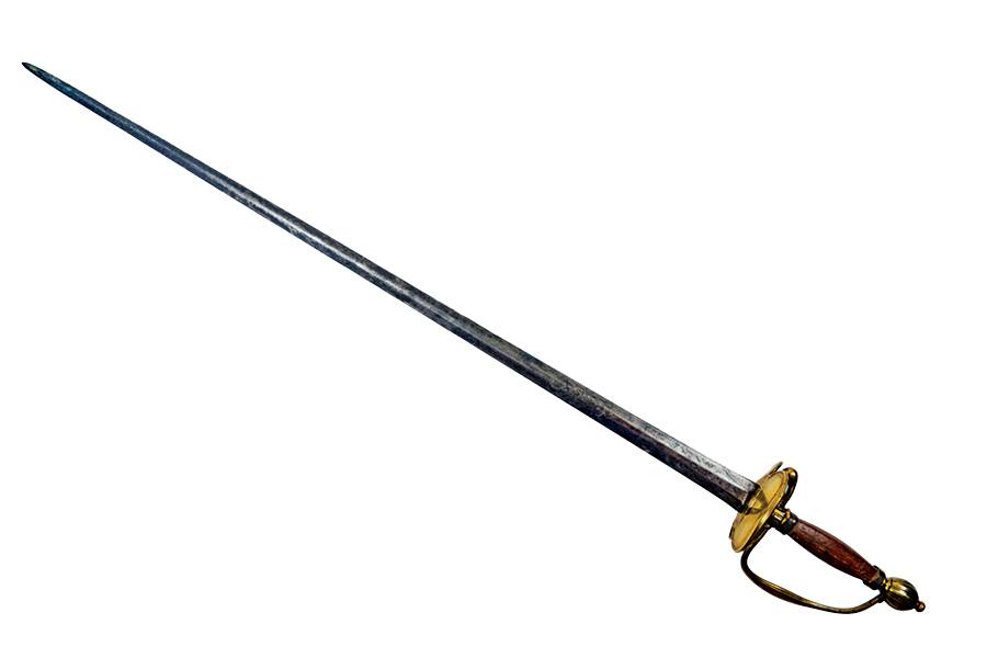 A long, slender sword with a slightly curved, narrow blade. The hilt features a wooden grip and a brass guard with a knuckle bow for hand protection. The blade appears aged with a darkened, weathered surface.
