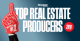 A hand wearing a black suit sleeve holds a large red foam finger shaped like a key with the text "WE'RE #1." Next to it, bold white text reads "TOP REAL ESTATE PRODUCERS" with "Boston Magazine" above and a red scalloped circle with "2026" inside on the right. The background is a gradient from light blue to dark blue.